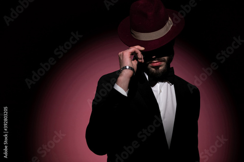 handsome mysterious businessman fixing his hat and hiding his eyes