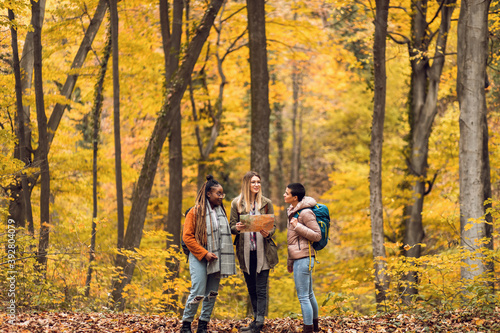 Three female friends having fun and enjoying hiking in forest on a beautiful autumn day. © Zoran Zeremski