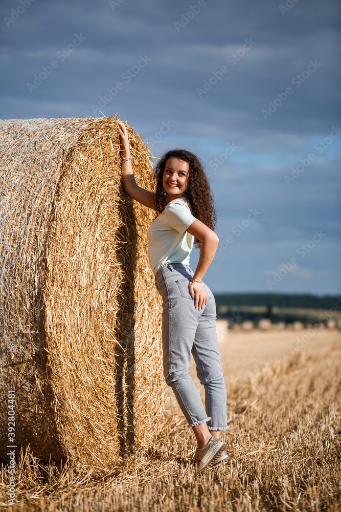 Beautiful girl near hay bales in the countryside. Girl on the background of haystacks Beautiful girl near hay bales in the countryside. Girl on the background of haystacks