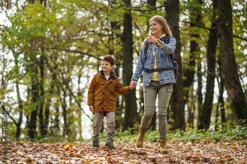 Happy mother and son are hiking in forest.