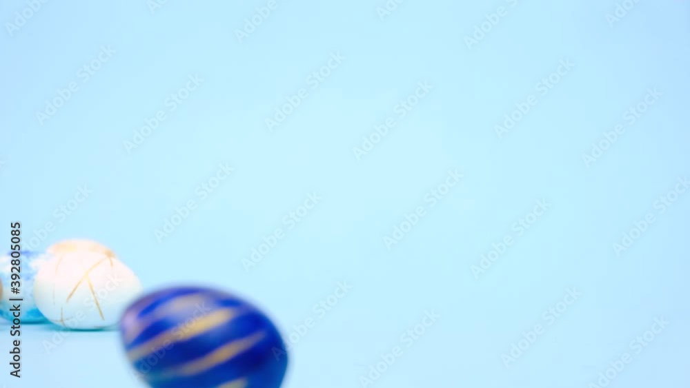 Easter eggs are rolling, knocking each other on blue table. Eggs trendy colored classic blue, white and golden . Happy Easter. Minimal style Easter eggs are rolling, knocking each other on blue table. Eggs trendy colored classic blue, white and golden . Happy Easter. Minimal style