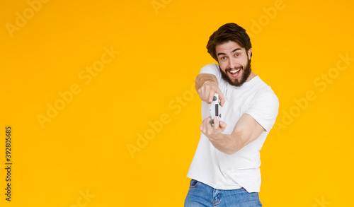 Portrait of his he nice attractive cheerful cheery glad guy playing cool new videogame online isolated over bright vivid shine vibrant yellow color background.