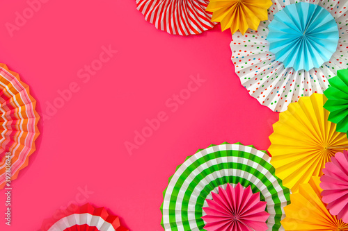 Colorful paper rosette and birthday garlands. Decorating for a party. Round  bright and color decoration. Pink background.