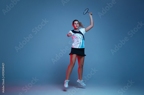 In jump. Beautiful handicap woman practicing in badminton isolated on blue background in neon light. Lifestyle of inclusive people, diversity and equility. Sport, activity and movement. Copyspace. © master1305