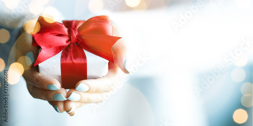 Hands holding little gift with red bow