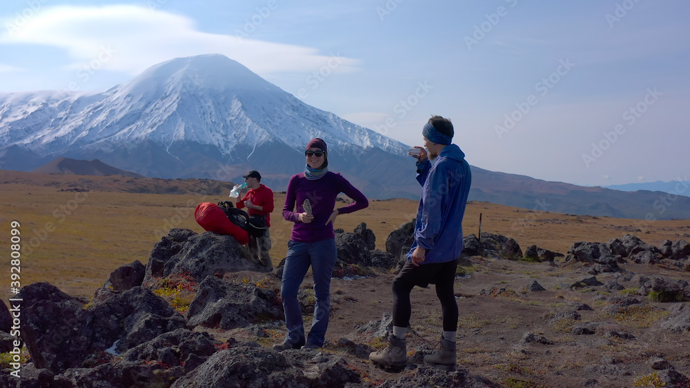One tourist man interviews the second tourist girl on the camera against the background of the volcanoes of Kamchatka.