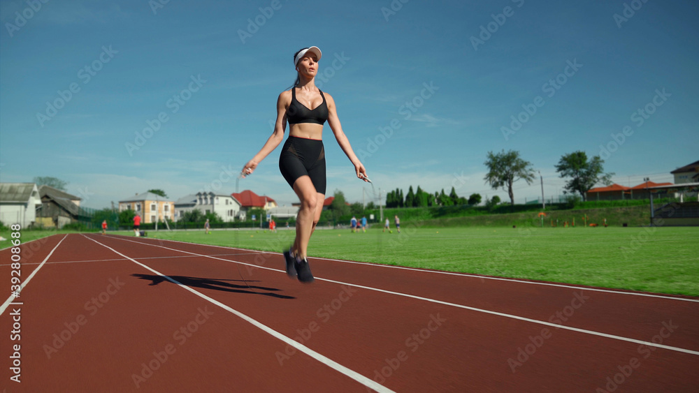 Athlete woman jumping using skipping rope outdoors.