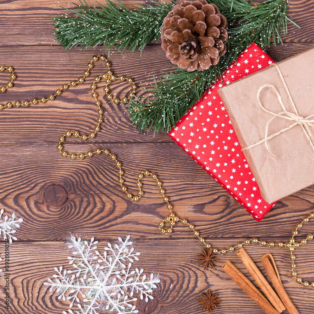 Christmas and New Year holiday background. Decor with gifts, fir branches, cones, Christmas decorations, beads, snowflakes, cinnamon sticks on a wooden table. Flat lay, empty space Christmas and New Year holiday background. Decor with gifts, fir branches, cones, Christmas decorations, beads, snowflakes, cinnamon sticks on a wooden table. Flat lay, empty space