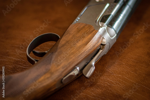 A sports rifle with a wooden butt lies on a brown background, close-up, soft focus