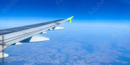 Panorama view of airplane wing, bright blue sky, flight on a passenger plane, view through the porthole, copy space