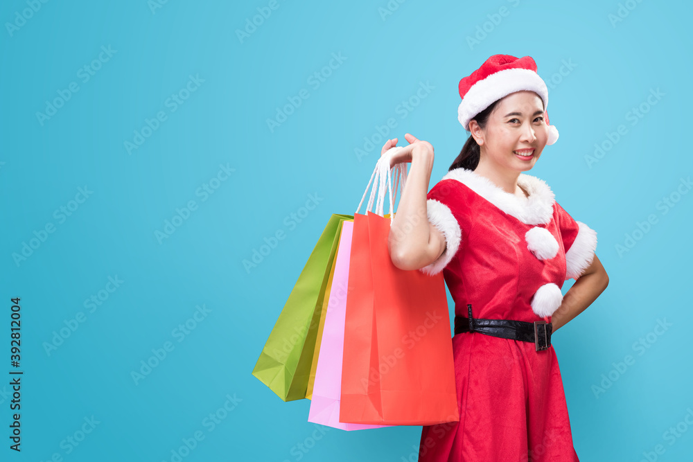 A beautiful woman in Santa Claus costume holding shopping bags on occasion of the Merry Christmas and Happy New Year A beautiful woman in Santa Claus costume holding shopping bags on occasion of the Merry Christmas and Happy New Year
