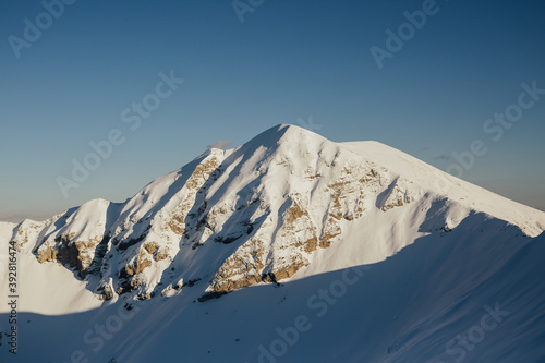 View of the mountain peak with stones and snow on it sunny winter day with blue sky.