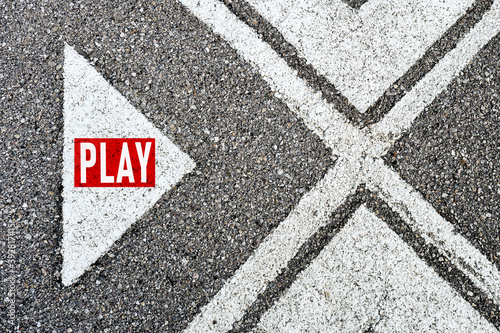 The word play written on asphalt road with direction arrows. Start to play sports game, music or multimedia movie. © Cagkan