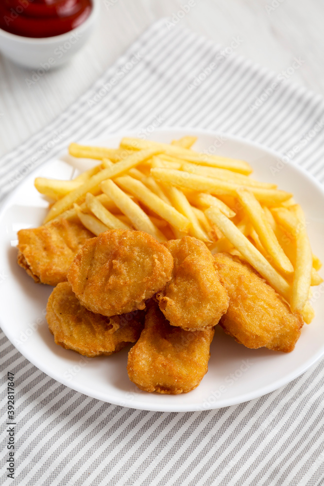 Tasty Fastfood: Chicken Nuggets and French Fries on a plate on a white wooden surface, side view. Close-up. Tasty Fastfood: Chicken Nuggets and French Fries on a plate on a white wooden surface, side view. Close-up.