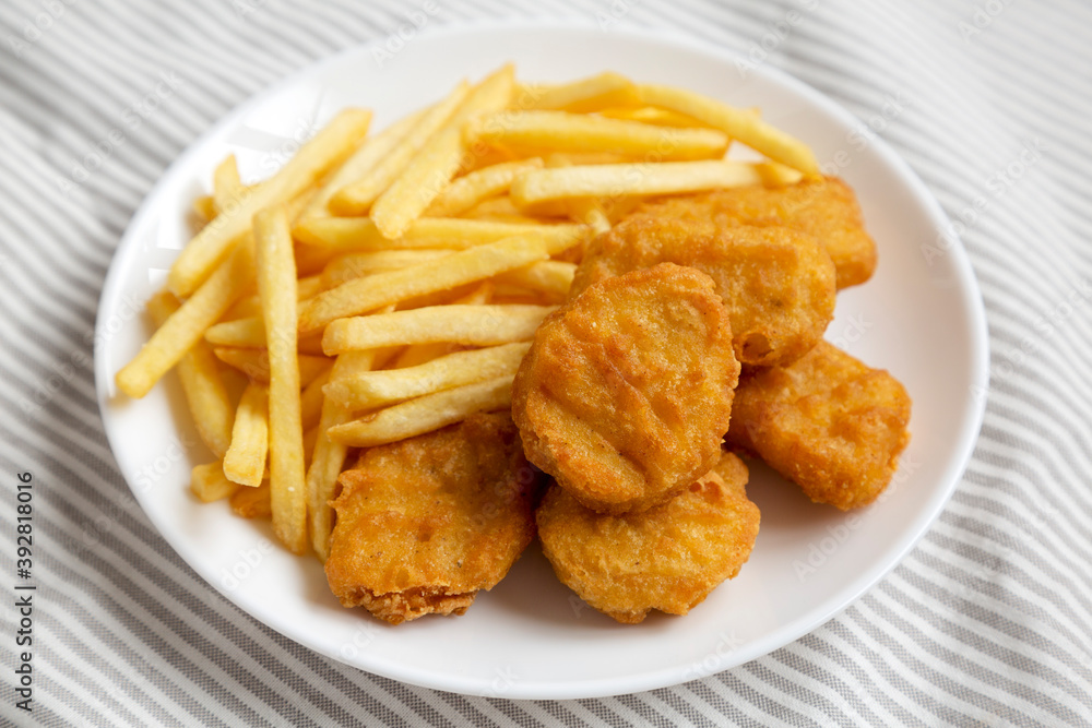 Tasty Fastfood: Chicken Nuggets and French Fries on a plate on cloth, low angle view. Close-up. Tasty Fastfood: Chicken Nuggets and French Fries on a plate on cloth, low angle view. Close-up.