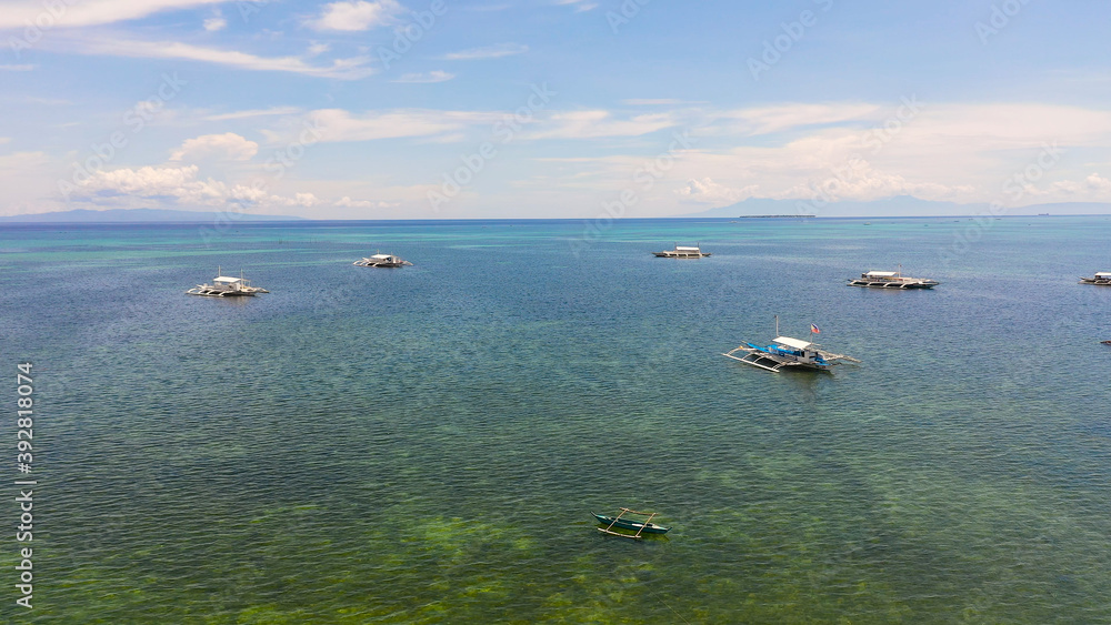 Aerial view of Traditional Filipino boats in the bay in turquoise water. Panglao, Philippines. Summer and travel vacation concept.