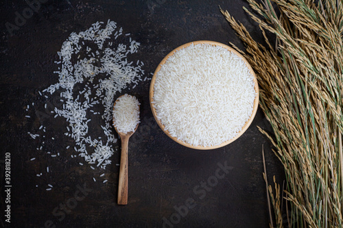 white rice (Thai Jasmine rice) in wooden bowl on dark wood background