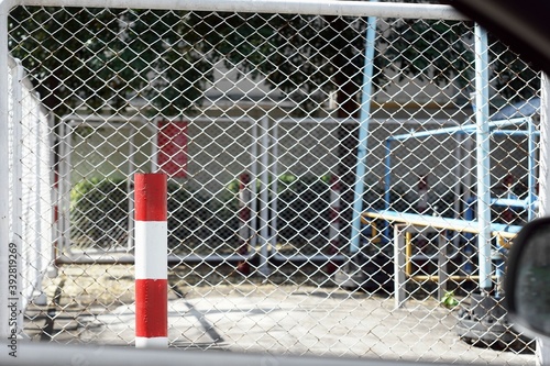 Close-UP a red-white pillar to sign danger  with a Steel mesh fence look out of the car. © jbstocks