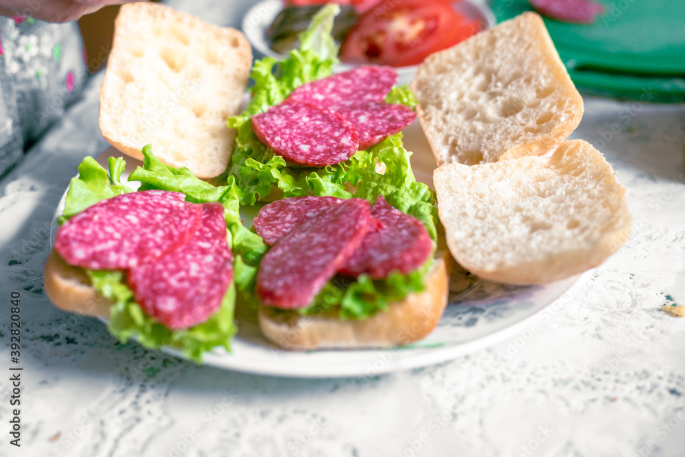 Preparing sandwiches with salami, tomato, pickles and lettuce Preparing sandwiches with salami, tomato, pickles and lettuce