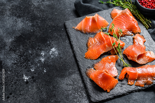 Smoked salmon slices with spices and herbs. Organic fish. Black background. Top view. Copy space