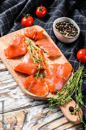 Smoked salmon slices with spices and herbs on cutting board. White background. Top view