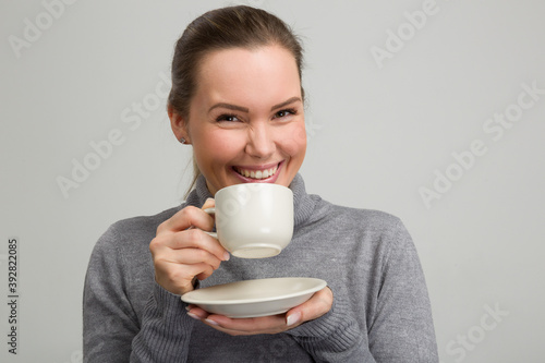 Young beautiful woman enjoying a cup of fresh coffee or tea in her hand 