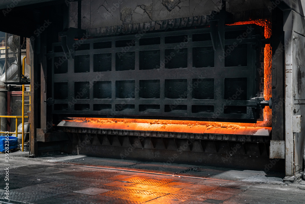 Big industrial furnace glowing red hot while heating and melting some scrap metal