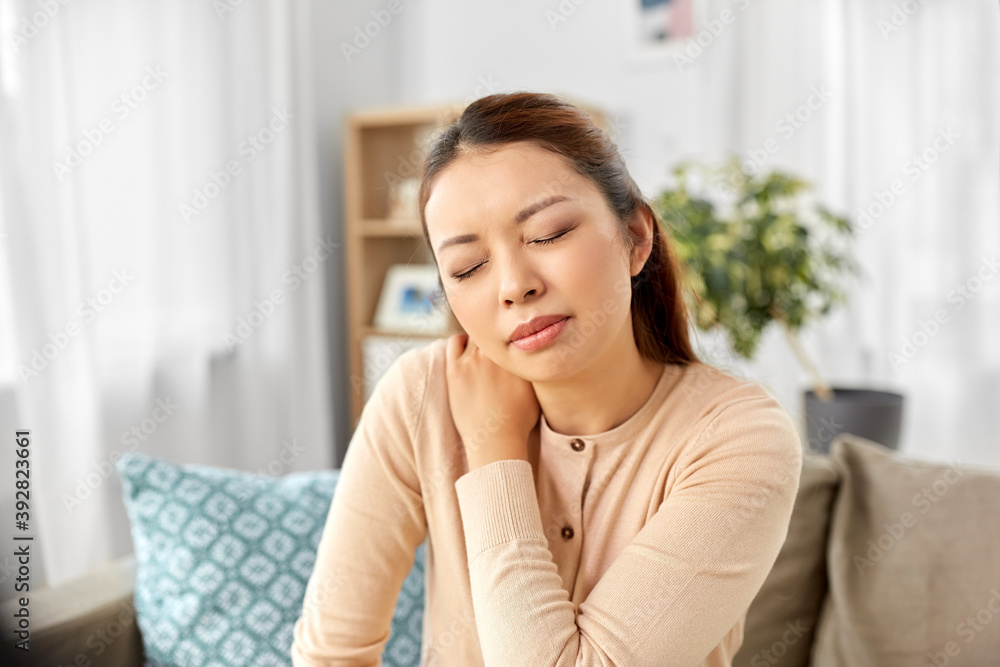 people, health and problem concept - tired asian woman suffering from ache in neck at home people, health and problem concept - tired asian woman suffering from ache in neck at home