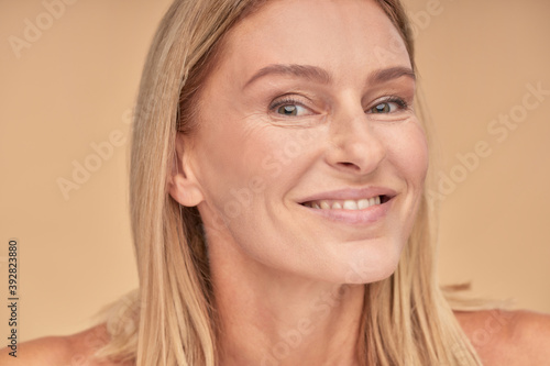 Feeling so beautiful. Portrait of a happy middle aged woman with clean skin and smiling at camera while posing over beige background