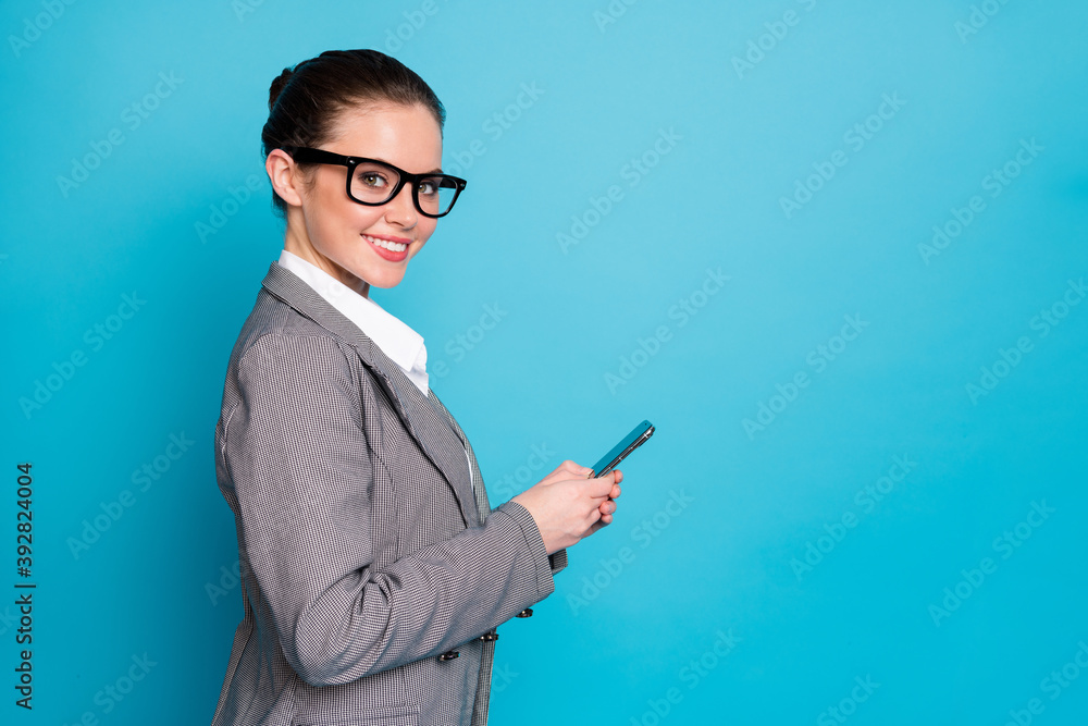 Profile side photo of positive girl broker use smartphone blogging wear blazer jacket isolated blue color background Profile side photo of positive girl broker use smartphone blogging wear blazer jacket isolated blue color background