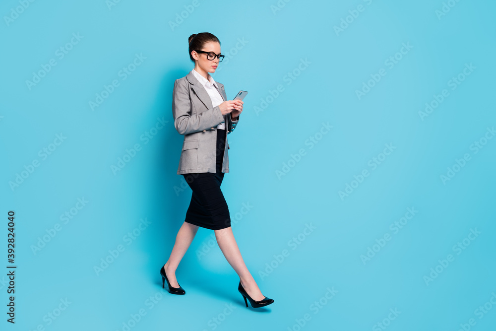 Full length profile side photo boss girl go use smartphone wear jacket skirt isolated blue color background Full length profile side photo boss girl go use smartphone wear jacket skirt isolated blue color background