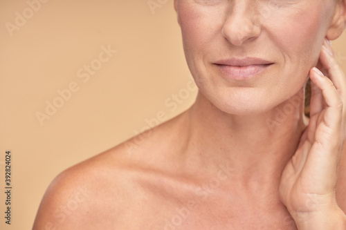 Smiling adult woman posing on beige background in studio