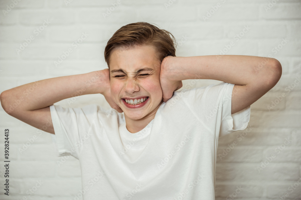 Upset teen boy closing ears and eyes . Portrait of angry guy tired of scandals or gossips. Negative emotion concept Upset teen boy closing ears and eyes . Portrait of angry guy tired of scandals or gossips. Negative emotion concept