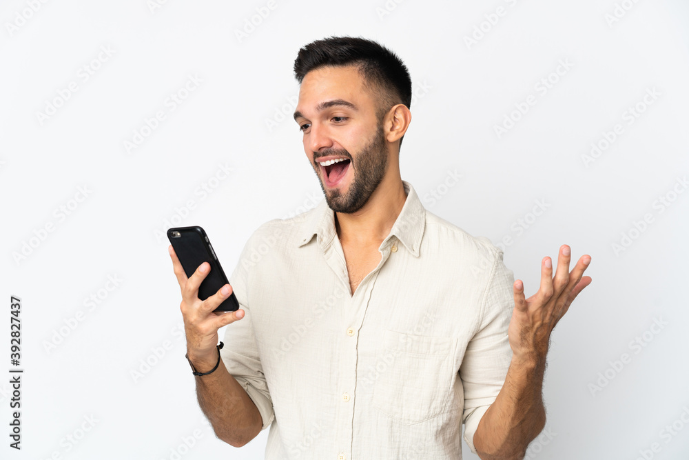 Young caucasian man isolated on white background looking at the camera while using the mobile with surprised expression Young caucasian man isolated on white background looking at the camera while using the mobile with surprised expression