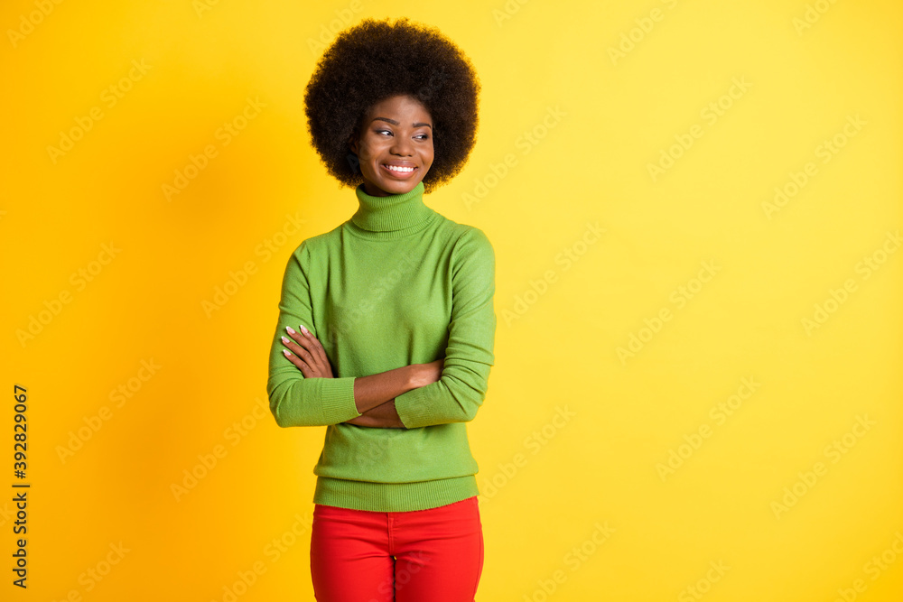 Photo portrait of serious african american woman with crossed arms watching to side isolated on vivid yellow colored background Photo portrait of serious african american woman with crossed arms watching to side isolated on vivid yellow colored background