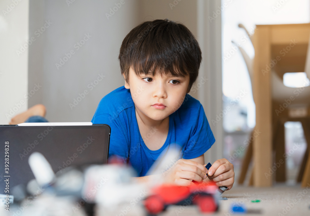 New normal life.Kid with bored face playing plastic blocks, Unhappy Child playing with toys alone in living room. Candid shot shot Young boy lying down on floor relaxing on his own at home. New normal life.Kid with bored face playing plastic blocks, Unhappy Child playing with toys alone in living room. Candid shot shot Young boy lying down on floor relaxing on his own at home.
