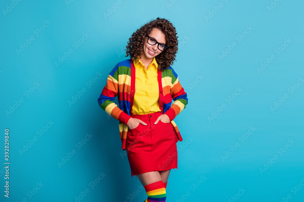 Portrait of pretty content cheerful wavy-haired girl holding hands in pockets isolated on bright blue color background Portrait of pretty content cheerful wavy-haired girl holding hands in pockets isolated on bright blue color background