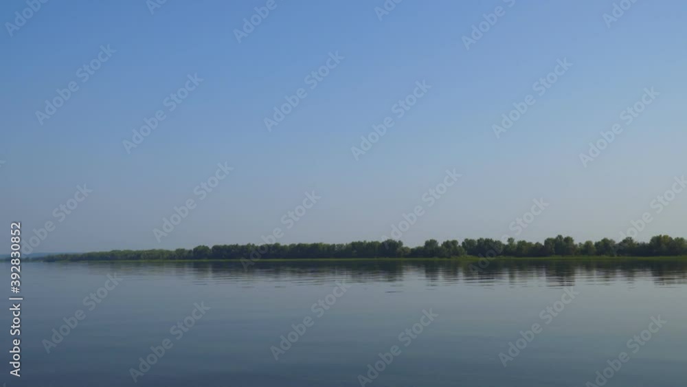 The camera moves over the water of a large river, on the Bank of which there is forest The camera moves over the water of a large river, on the Bank of which there is forest