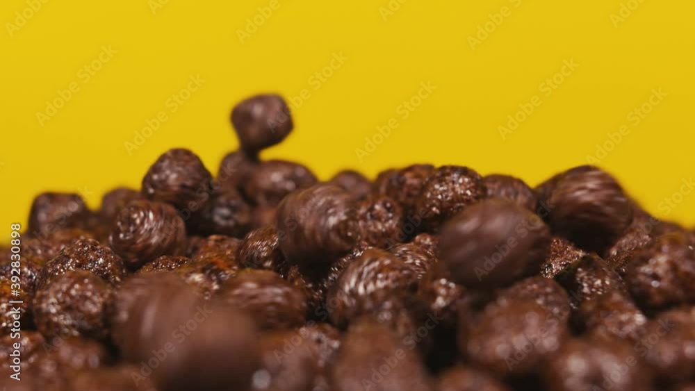 Chocolate corn cereal balls falling, filling the frame. Serving breakfast. Close up. Slow motion Chocolate corn cereal balls falling, filling the frame. Serving breakfast. Close up. Slow motion