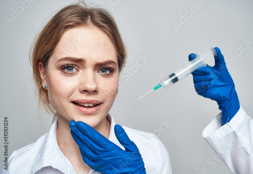 female patient smiling and a syringe in the hands of the doctor botox injection