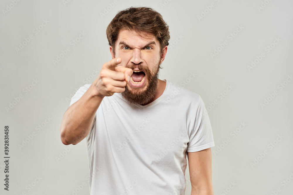 bearded man gesturing with his hands in a white t-shirt aggression light background bearded man gesturing with his hands in a white t-shirt aggression light background