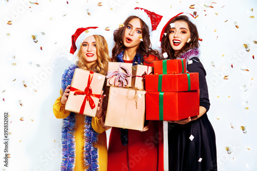 Happy party moments of fashionable women with presents. Christmas young women posing on white background. Presents, gift, holidays, people and celebration concept.