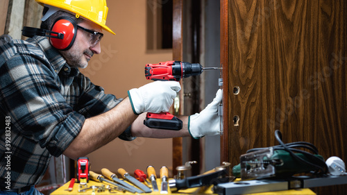 Close-up. Carpenter at work repairs and installs the new lock of a wooden door. Construction industry. 