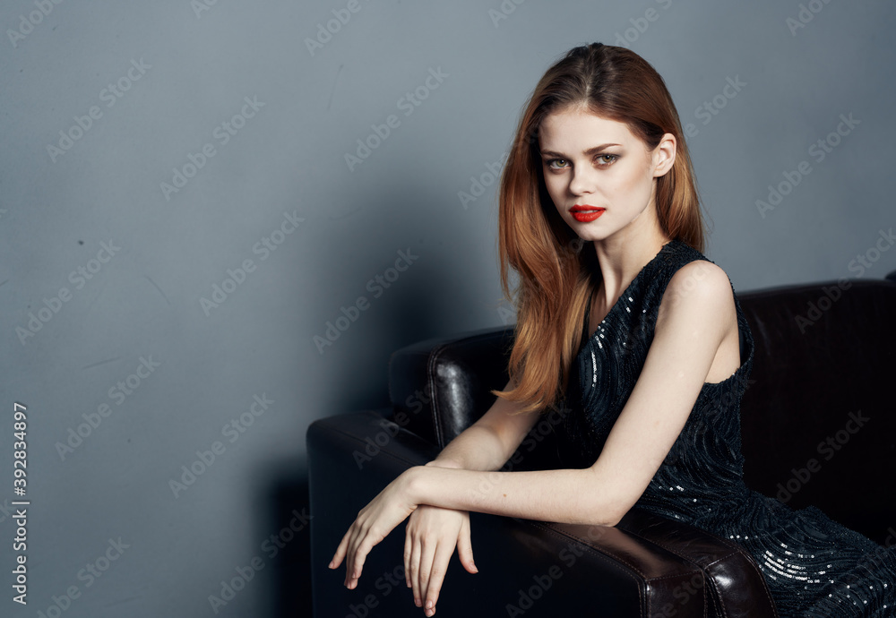 Charming Woman in Black Dress on a Leather Sofa Bright Makeup Model