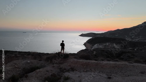 Aerial jib up shot of a man standing on top of a hill on Fyriplaka beach just after sunset photo