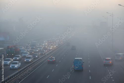 cars driving in the city in the morning mist
