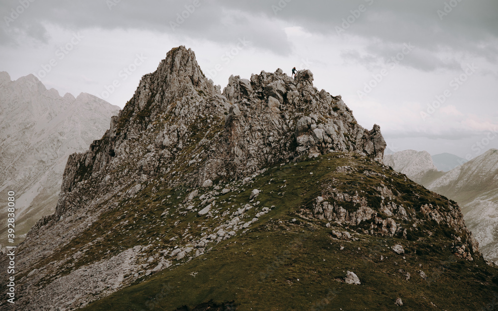 Hiker on top of rock formation in valley of mountains Hiker on top of rock formation in valley of mountains