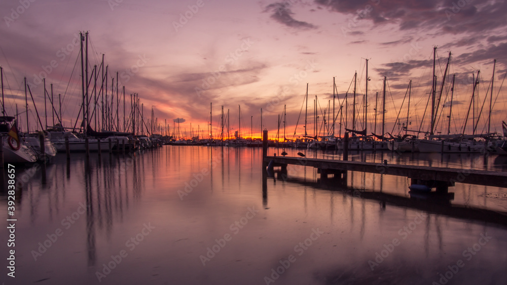 Silhouettes of sailing boats and piers in dutch harbour at dusk