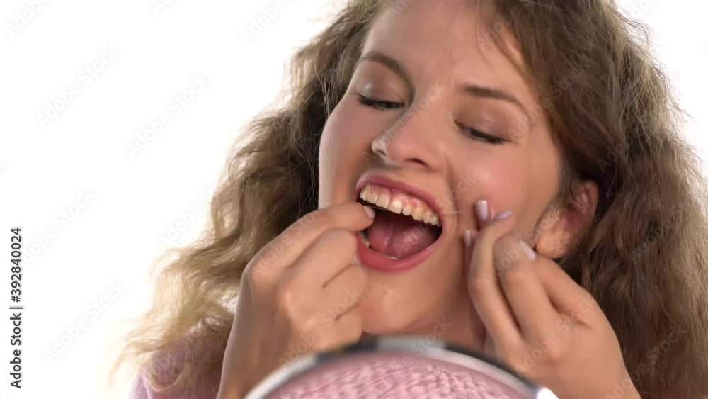 a young woman who cleans his teeth with dental floss on a white background a young woman who cleans his teeth with dental floss on a white background