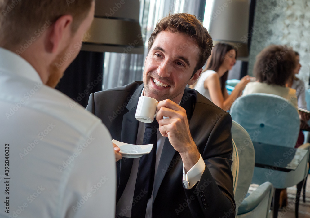 Colleagues and friends. Two cheerful businessmen drinking coffee and talking to each other Colleagues and friends. Two cheerful businessmen drinking coffee and talking to each other